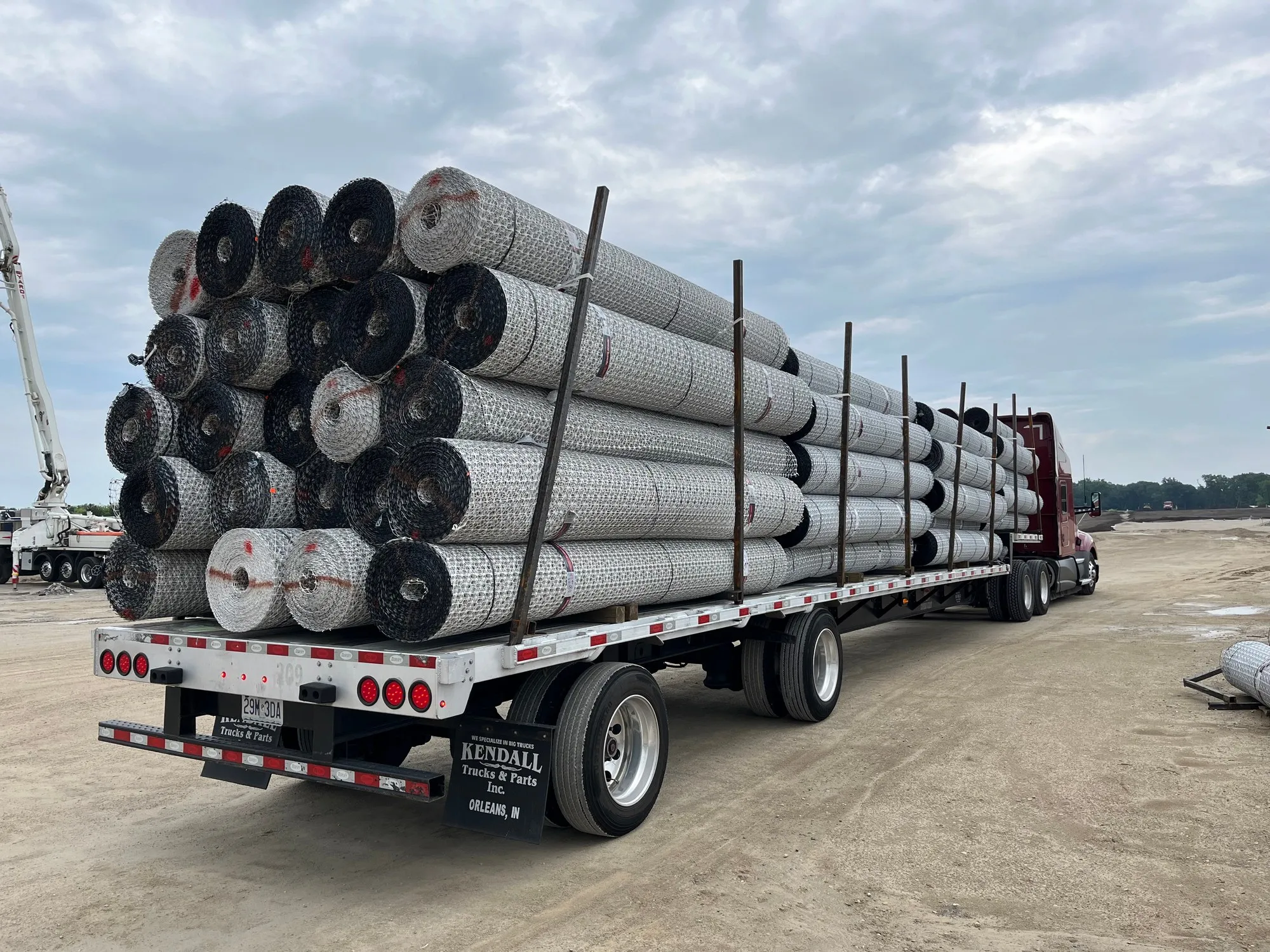 Flatbed truck loaded with geogrid rolls arriving at a jobsite