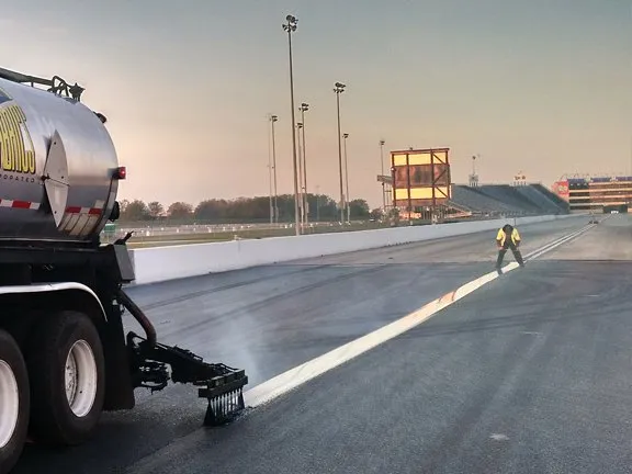 Sealant truck applying a membrane band at a racetrack at dawn