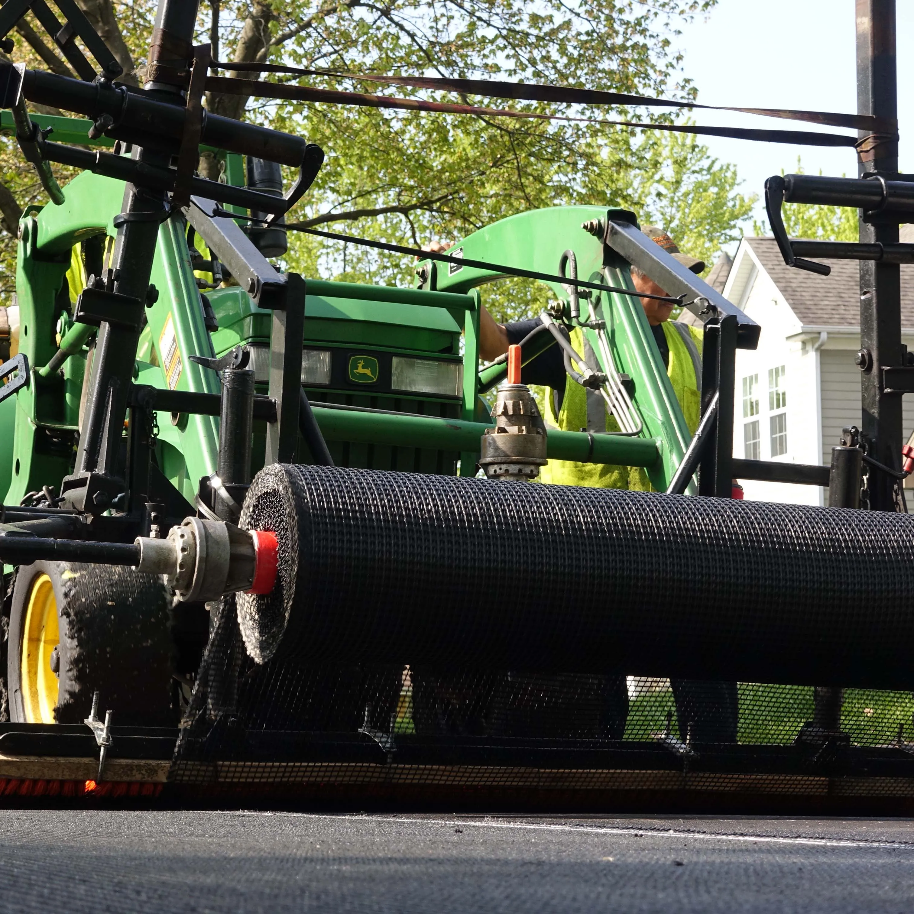 Crew installing a reinforcement grid interlayer ahead of paving